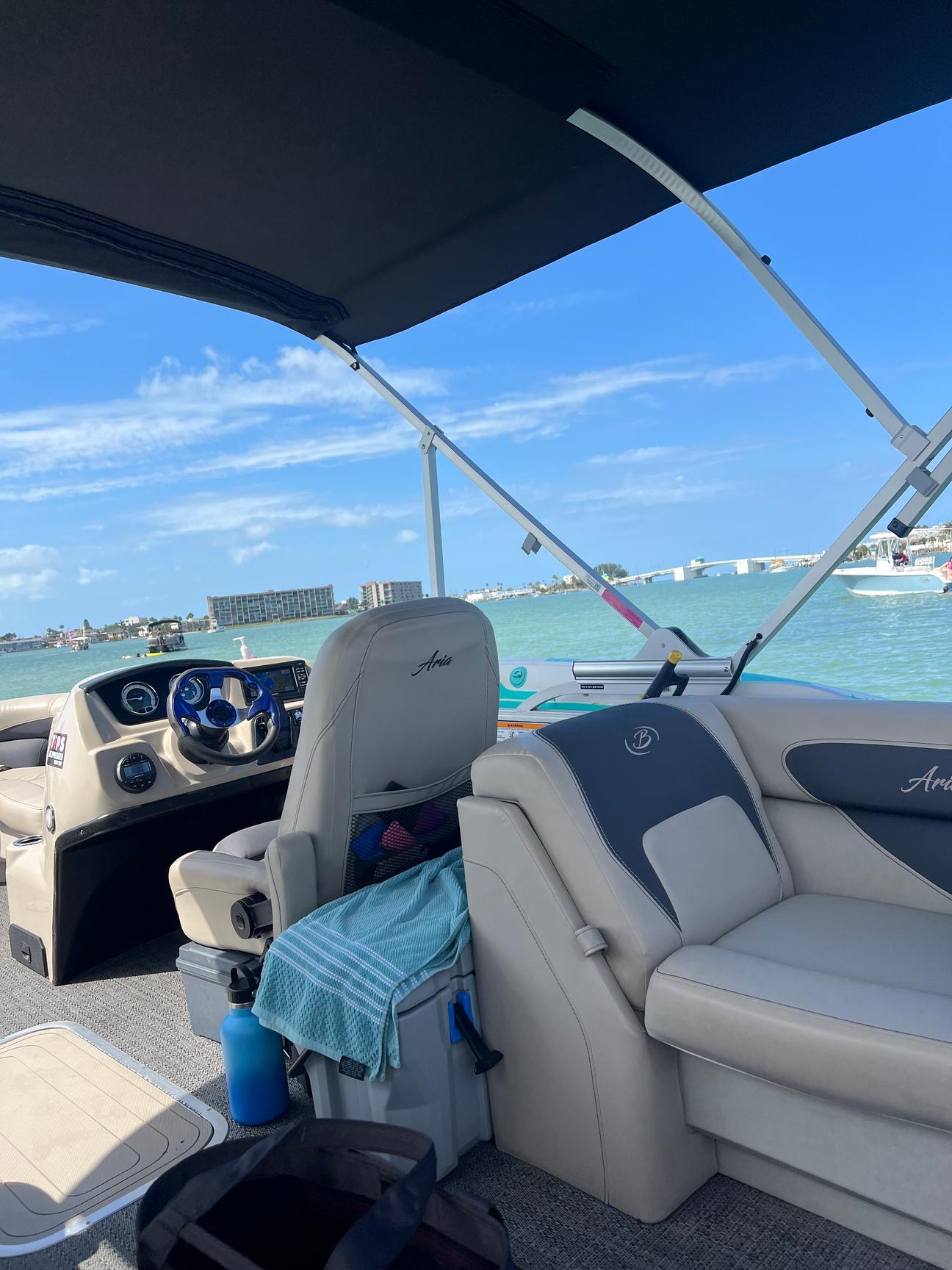 Comfortable seating and helm aboard the 2024 Barletta pontoon under its bimini top on the water