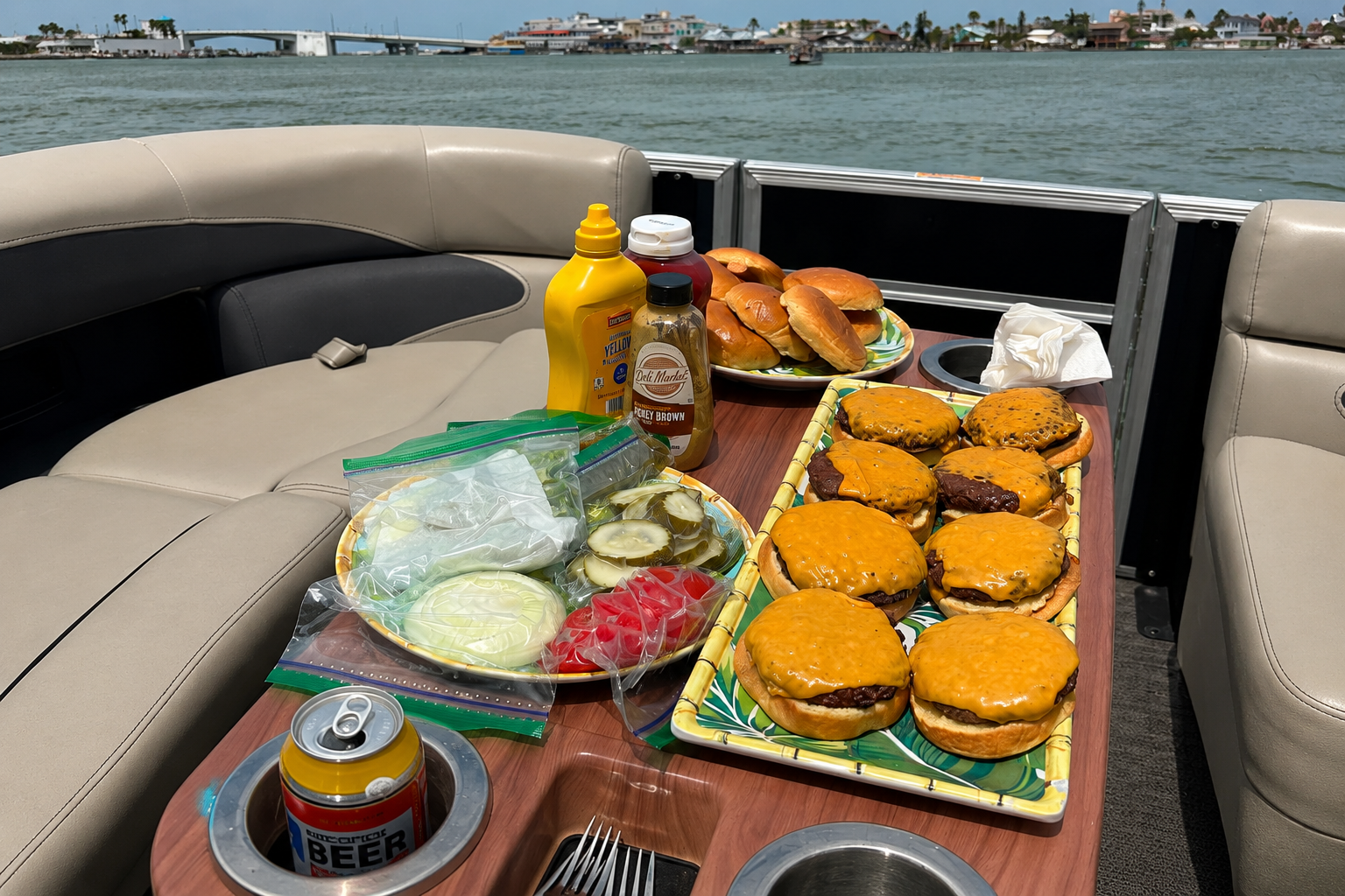 Freshly grilled cheeseburgers, buns and fixings laid out on the boat's table with the intracoastal waterway behind